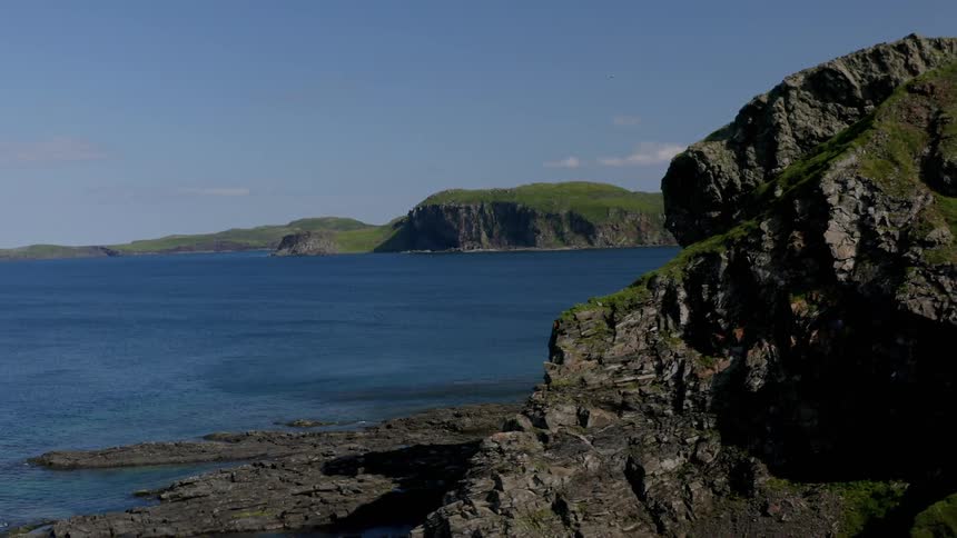 The blue ocean touches the rocks on the shore