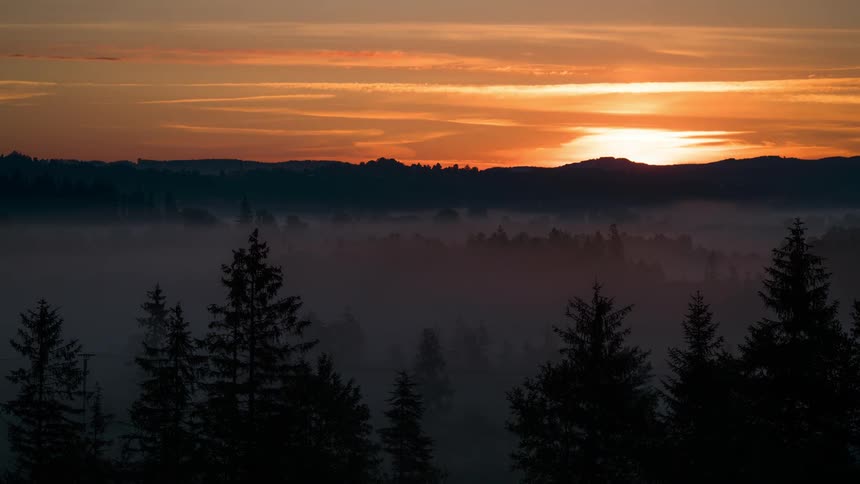 Silhouette of mountains and forests against a reddish sky at dawn