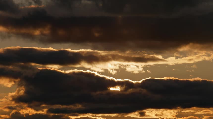 The sun shines from behind dark storm clouds