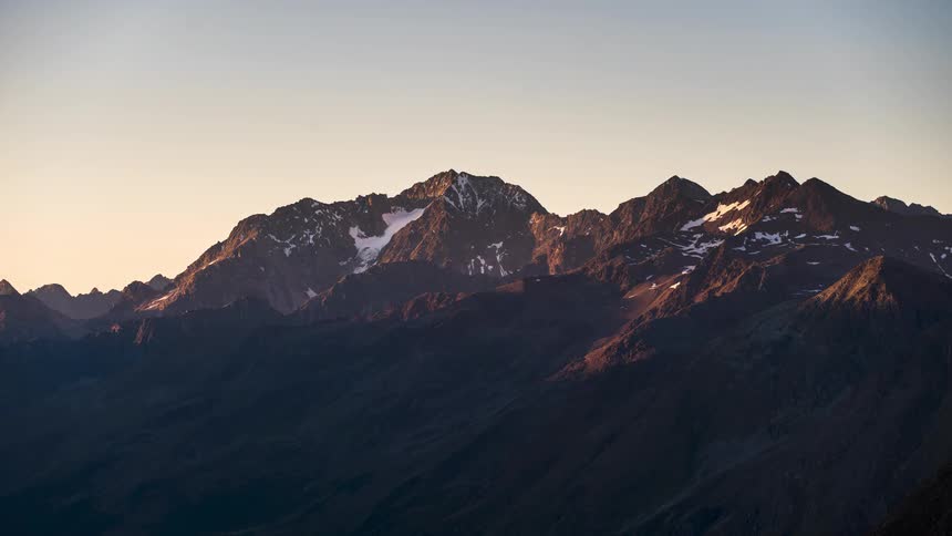 A mountain range and its dusk and the sky is turning orange