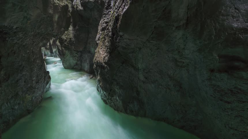 Time lapse of a turbulent river flowing through a narrow rocky gorge with milky turquoise water