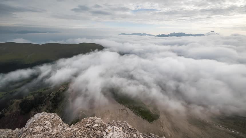 Landscape of clouds passing above mountains