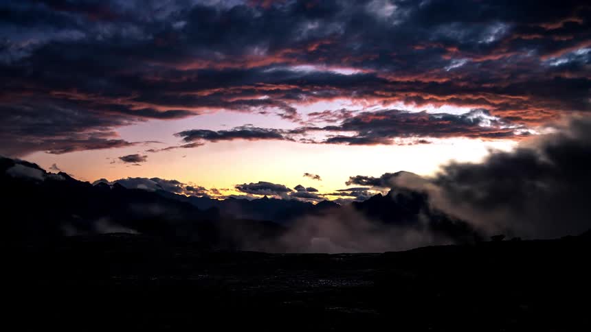 Landscape with the silhouette of mountains and clouds passing by in timelapse at dawn