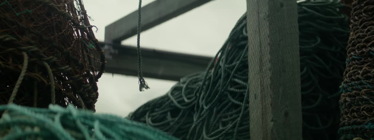 A rope dangles over big piles of rope within a crude structure