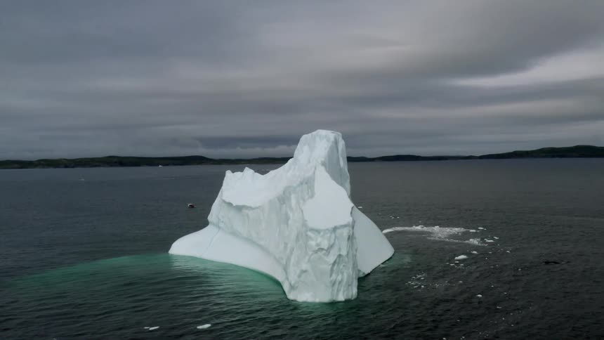 Aerial view of a solitary iceberg floating in the ocean with overcast skies