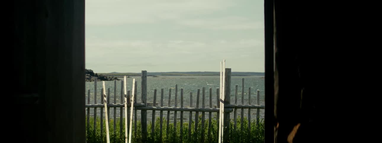 A view of a bay of still water and in front there is a small wooden fence