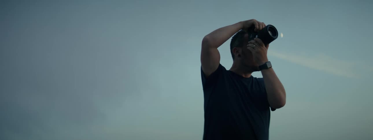 Man in a black tshirt holding and photographing with a professional camera