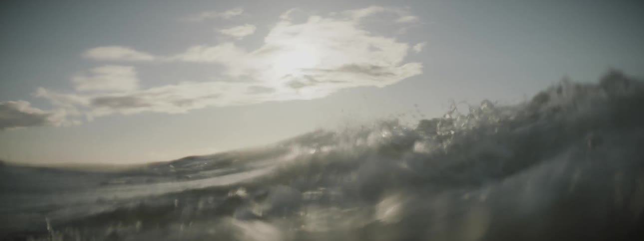 Looking up through the dark water to the sun shining on top of the waves