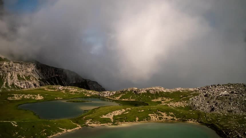 Serene lakes surrounded by rocky mountains and low clouds