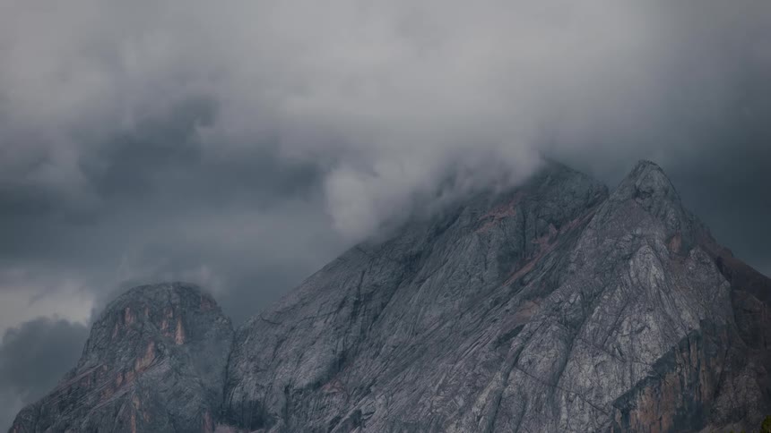 Rocky mountain with cliffs and black clouds passing by