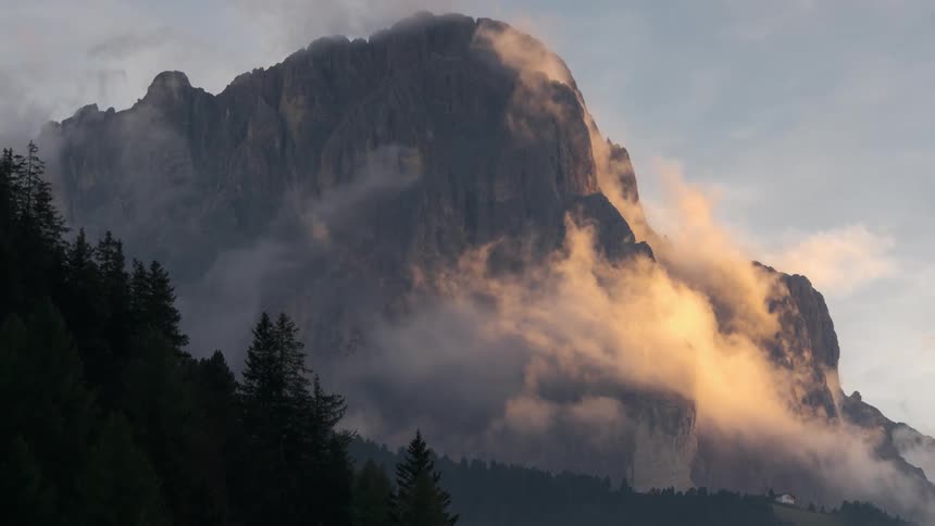 Low lying clouds flowing over forest and mountains reflect sunlight