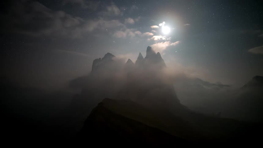 Silhouette landscape of mountains with clouds passing by and the sun highlighted on a dusk day