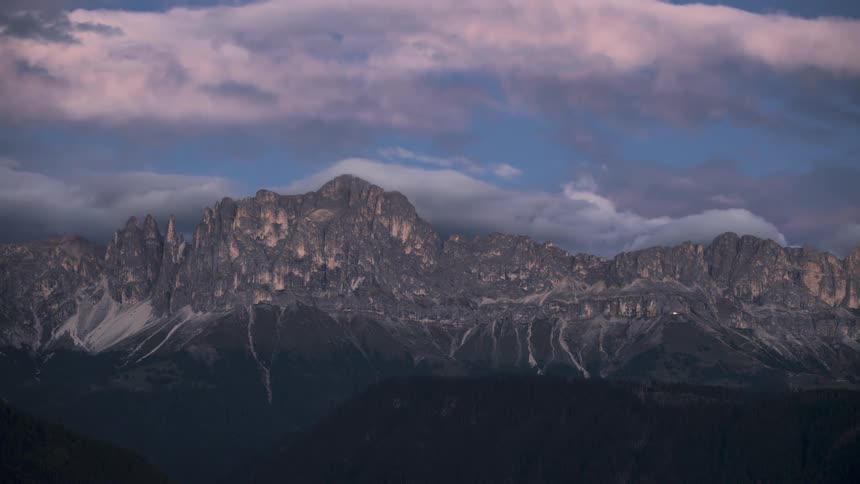 Mountain range with irregular peaks and steep slopes illuminated by a soft light at dusk