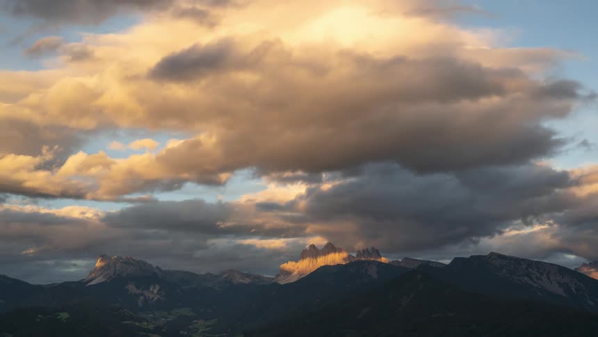 Time lapse of clouds rolling over a mountainous terrain at dusk