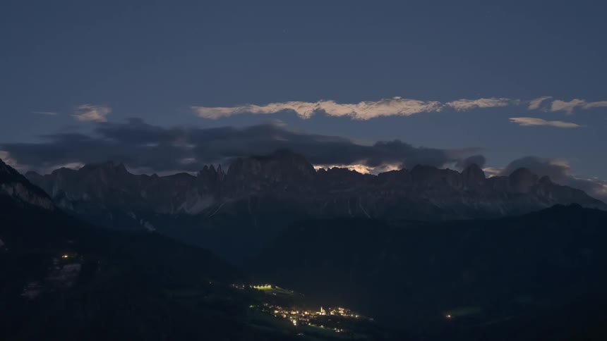 A mountain range at night and then it dawns and the sun rises from behind the mountains