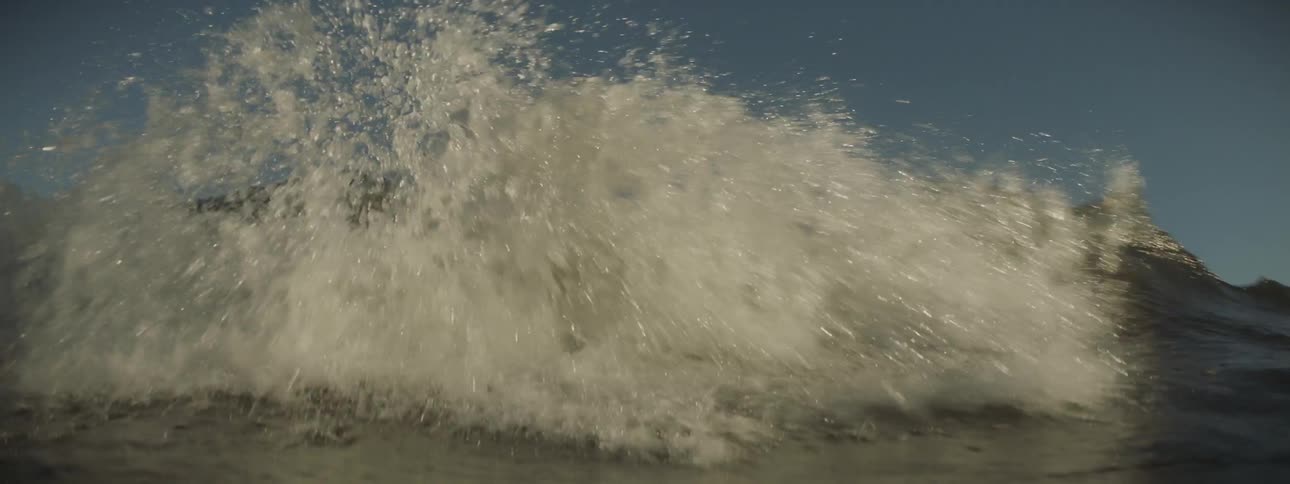 A wave crests and crashes during the day