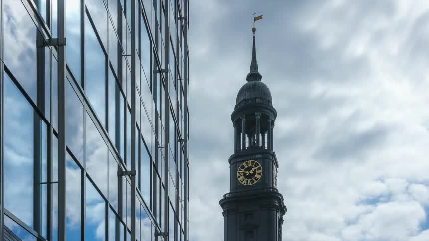 Atower with a clock in contrast to the sky with clouds passing quickly
