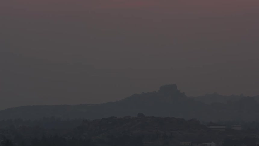 The orange sun in the sky is going down and its getting dark