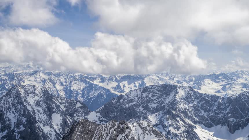Large numbers of clouds move over an enormous range of mountains
