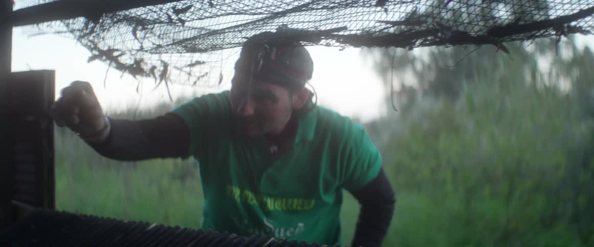 A man works at fixing a metal structure in a rural setting