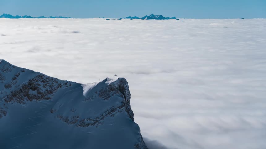 A sea of white clouds seen from the top of a snowy mountain
