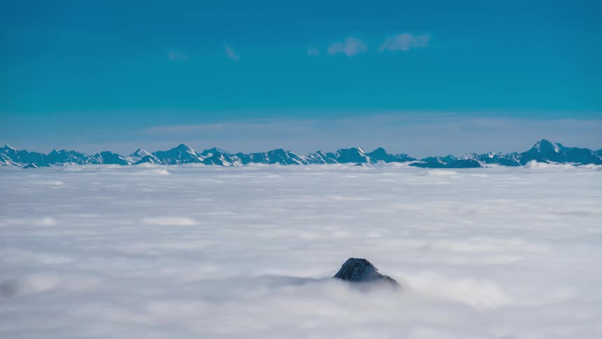 Clouds completely obscure a large mountain valley save for a range and a single mountain peak