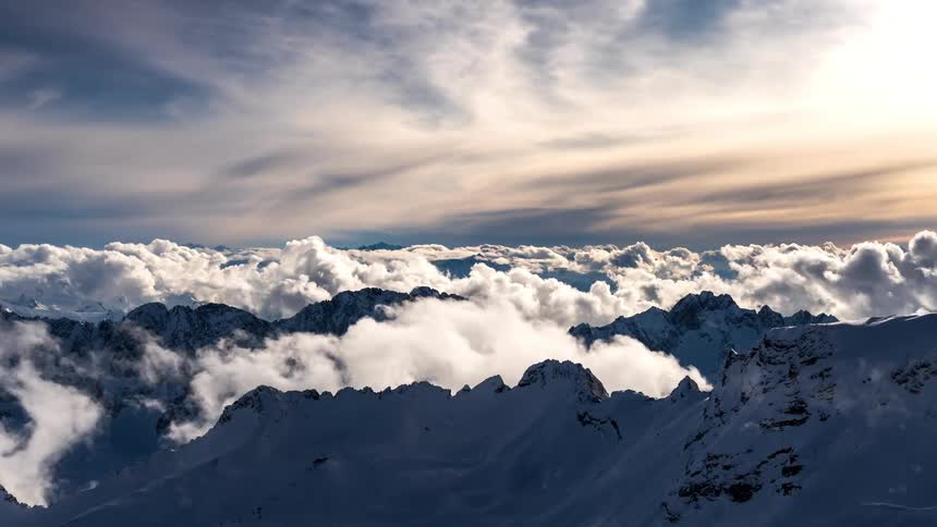 Clouds flow over the snow covered mountain