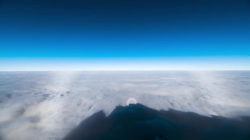Sun shines onto peak of shadow cast by mountain on moving cloud layer