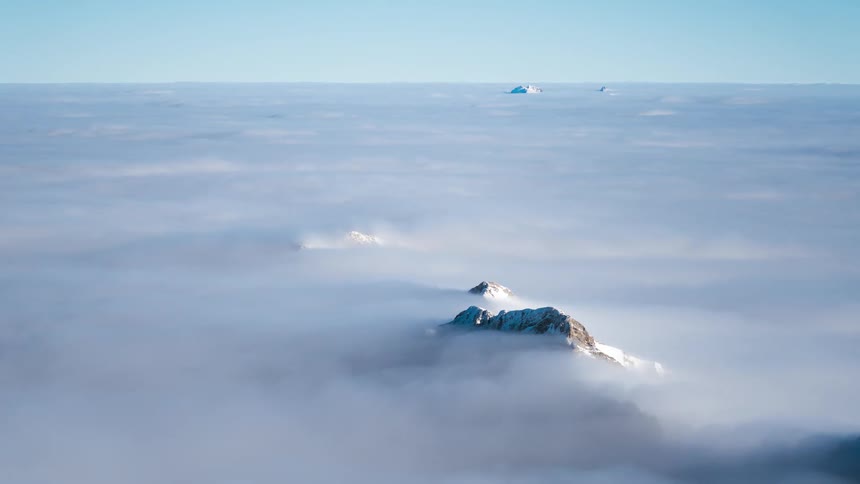 Sea of clouds covering mountain peaks with snow