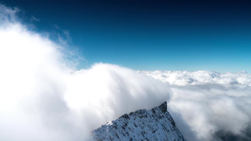 Massive cloud banks roll over the peaks of several mountains