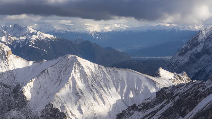 A mountain range with clouds moving over it shot from the air