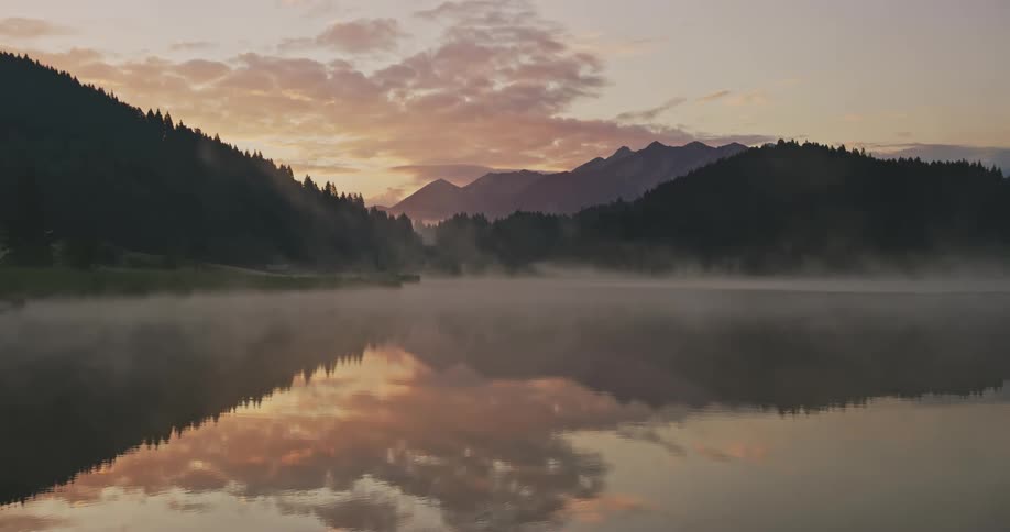 A lake reflects forests and mountains around it
