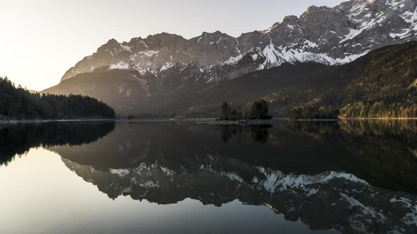 Waterfowls move across the lake reflecting the nearby forests and mountains