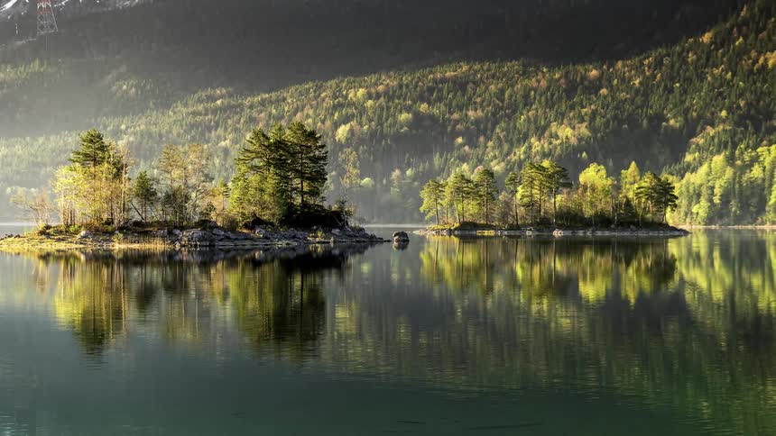 A large lake of water reflecting trees in a forest on a mountain