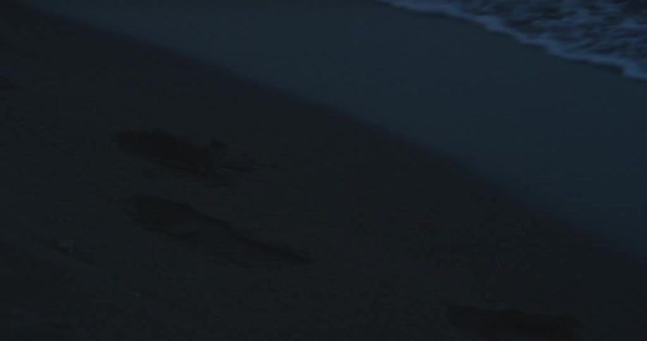 The sand of a beach with footprints and waves of sea waves hitting the sand and returning back