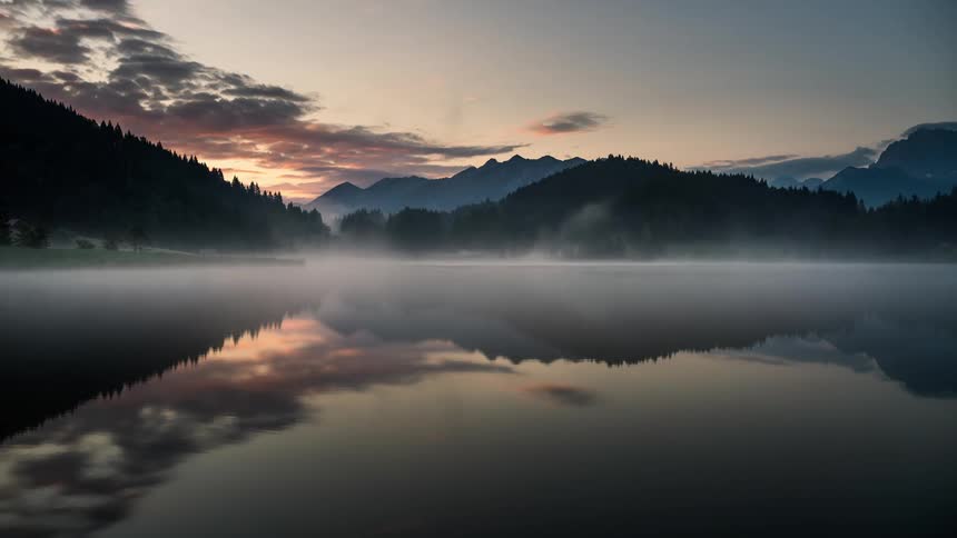 A lake with fog on the surface passing in all directions until dawn when the sun appears the fog disappears