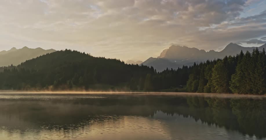 Time lapse of light mist rolling over a tranquil lake at sunset
