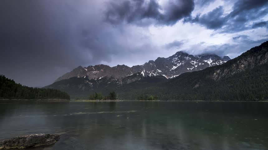 A surface of a lake with the movements on its surface and it is reflecting the clouds and mountains back