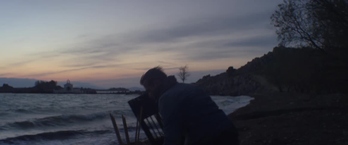 A man sets up a board on a beach at dusk