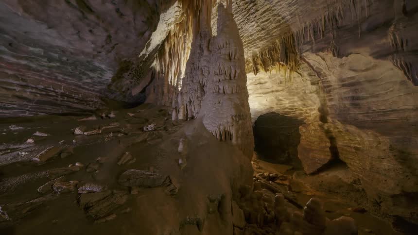 Light illuminates large cavernous chamber leading into a dark tunnel