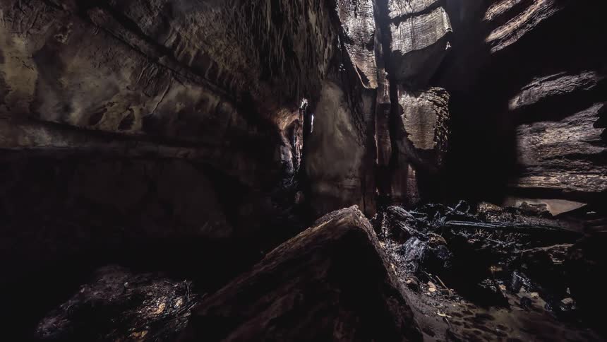 A hole in a canyon with stone walls and light coming from above