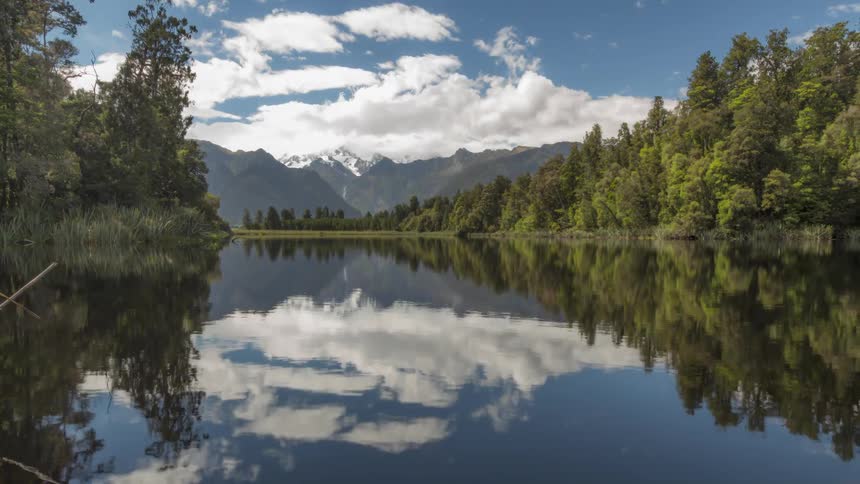 Clouds moving over mountains reflect in a lake