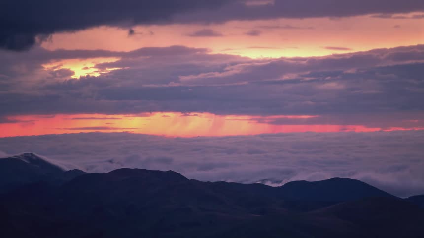 Silhouette landscape of a mountain with a sea of clouds in a purple and reddish sky