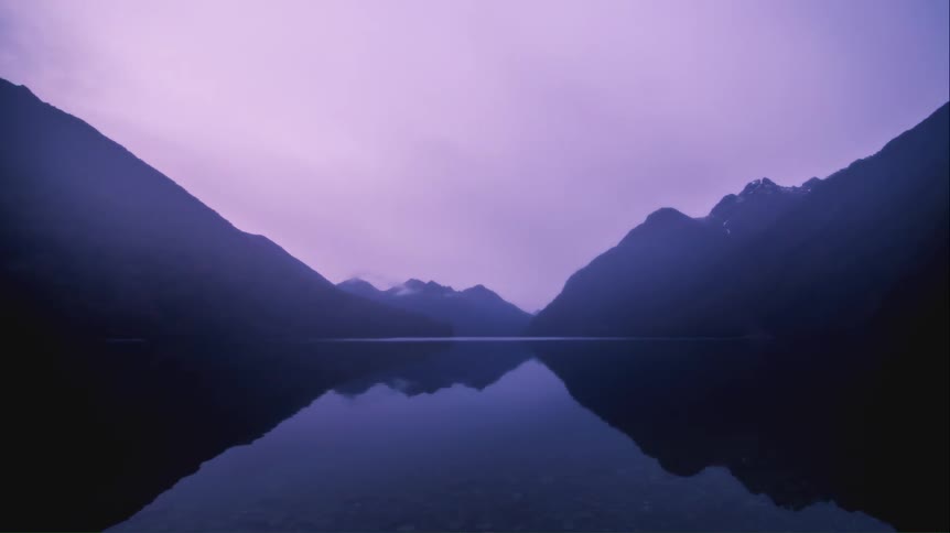 Clouds move over a lake sandwiched by large mountain ranges