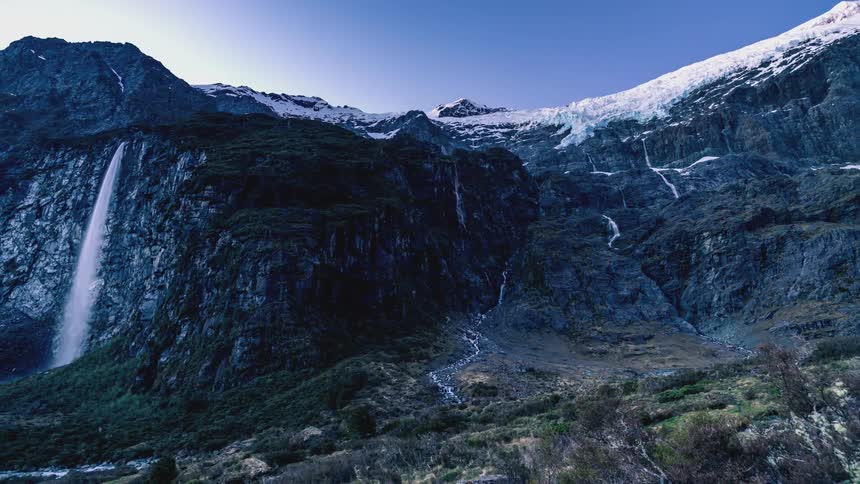 Waterfalls cascade down the side of mountains in a valley