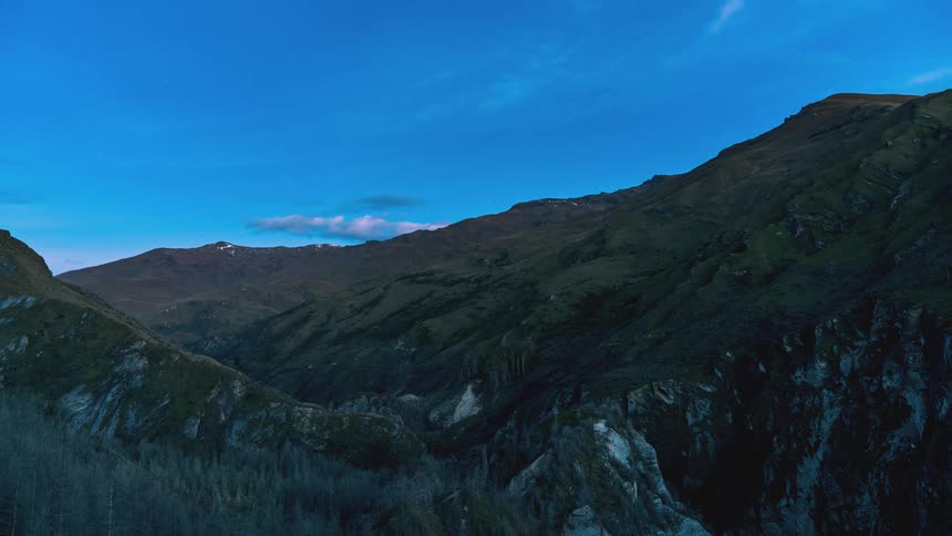 Mountainous landscape at twilight with a clear sky transitioning to darker tones