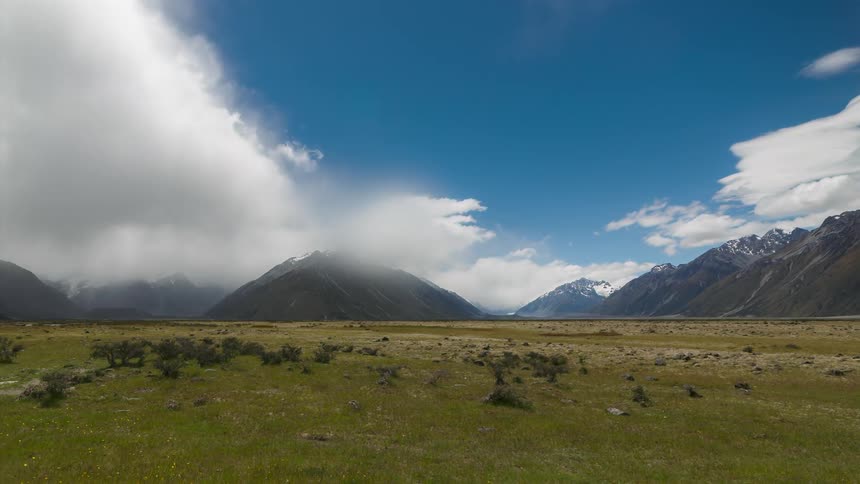 Time lapse of clouds rolling over mountains under a cloudy sky
