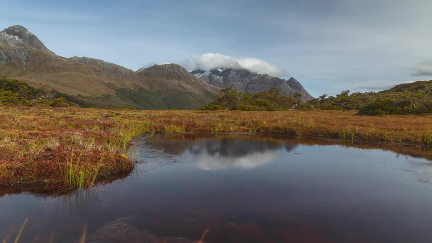A small body of water near a plain and surrounded by mountains
