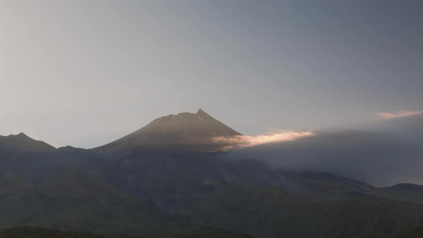 Mountainous landscape with a prominent peak in the background shrouded in mist