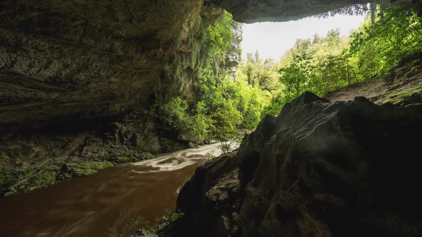 River of muddy water flowing through a rocky canyon with vegetation on the edges